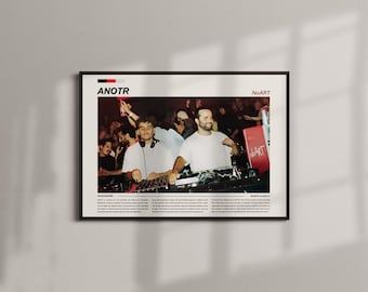 May include: A framed poster featuring a photograph of two DJs performing at a crowded event. The poster has the text "ANOTR" at the top, with "NoART" in the upper right corner. The image is in a black frame.