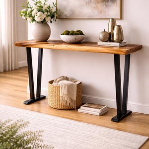May include: A wooden console table with black metal legs. The table is decorated with a vase of white flowers, decorative vases, a marble bowl with green spheres, and a woven basket. A rug and artwork are also visible.