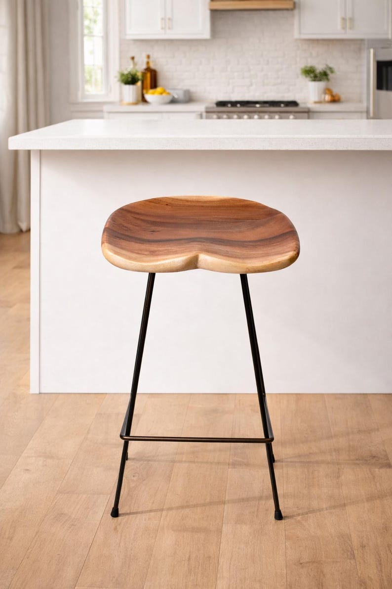 Puede incluir: Un taburete de bar de madera con asiento contorneado y patas de metal negro. El asiento es de madera natural con un patr&oacute;n de vetas &uacute;nico. El taburete est&aacute; dise&ntilde;ado para uso en cocina o bar.