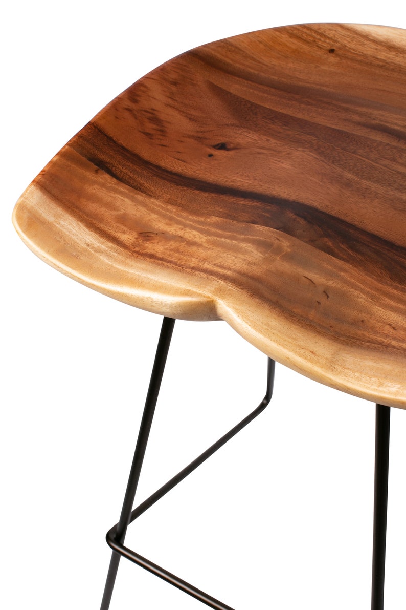 Puede incluir: Taburete de bar de madera con asiento de borde vivo y patas de metal negro. El asiento es de madera natural con un acabado marr&oacute;n claro y una forma &uacute;nica. Las patas son finas e inclinadas, proporcionando estabilidad.