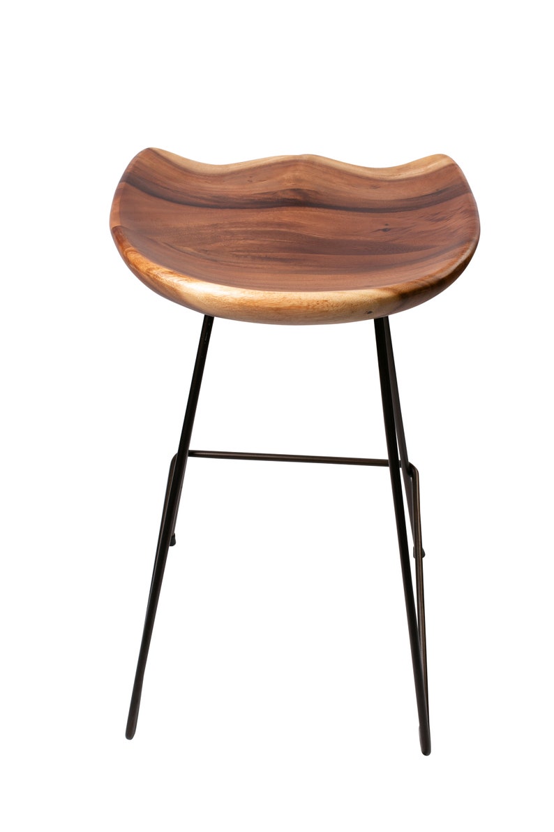 Puede incluir: Taburete de bar moderno con asiento de madera natural y patas de metal negro. El asiento tiene un dise&ntilde;o curvo &uacute;nico y un color marr&oacute;n c&aacute;lido. Las patas son delgadas e inclinadas, proporcionando una base estable.