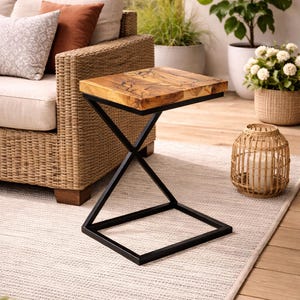 May include: A square side table with a natural wood top and a black metal base. The table is approximately 20 inches square and 20 inches high. The table is on a light-colored rug.