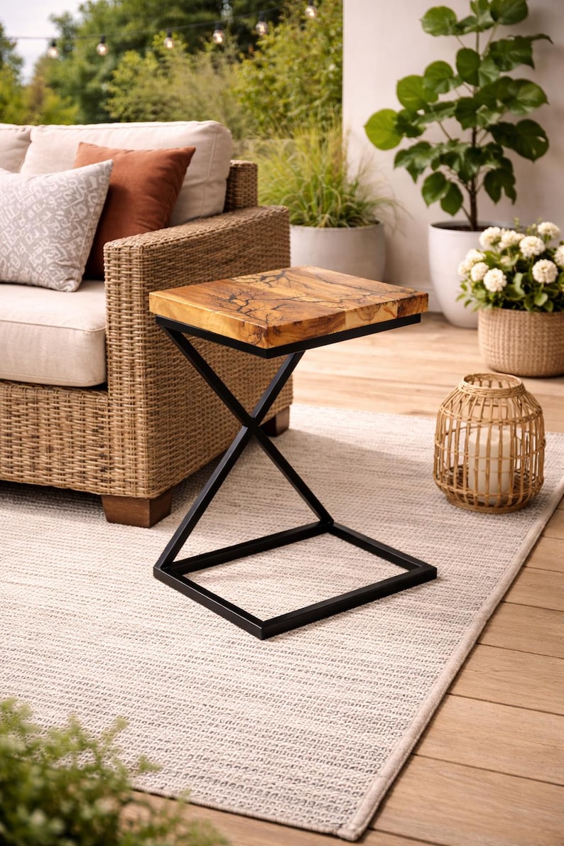 May include: A square side table with a natural wood top and a black metal base. The table is approximately 20 inches square and 20 inches high. The table is on a light-colored rug.