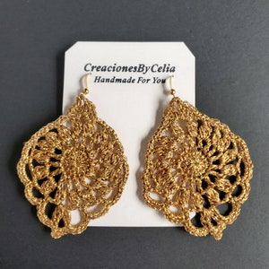 Puede incluir: Pendientes de crochet dorados con un diseño delicado e intrincado. Los pendientes están hechos a mano y presentan una pequeña perla redonda dorada en la parte superior de cada pendiente. Los pendientes están etiquetados como "CreacionesByCelia Handmade For You".