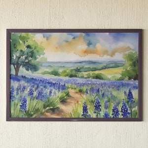 May include: Watercolour painting of a field of purple wildflowers with a path leading through the centre. The field is surrounded by rolling hills and a blue sky with white clouds.