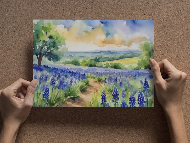 May include: Watercolour painting of a field of purple flowers with a path leading through the centre. The background features a green hillside and a blue sky with white clouds.