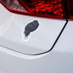 May include: A black and white sticker of a deep sea anglerfish with a bioluminescent lure on a white car bumper.