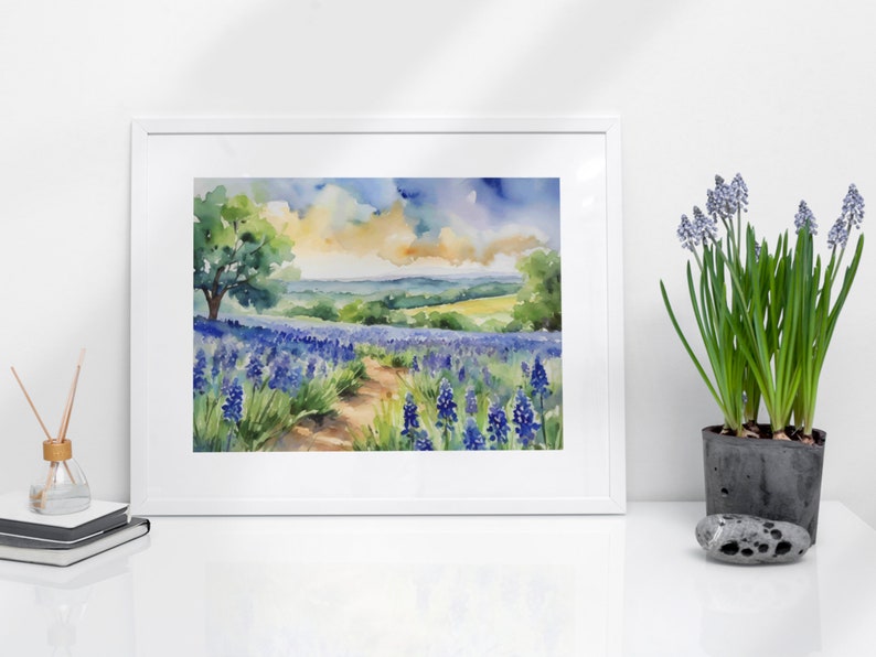 May include: Watercolour painting of a field of bluebonnet flowers with a dirt path leading through the field. A lone tree stands in the distance, and the sky is a mix of blue, yellow, and white.