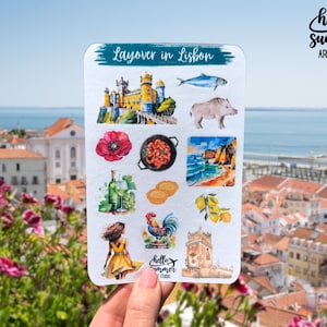 May include: A sticker sheet featuring watercolour illustrations of Lisbon, Portugal. The sheet includes images of a castle, a fish, a pig, a poppy, shrimp, a beach scene, wine, bread, lemons, a woman in a yellow dress, a rooster, and a tower. The text "Layover in Lisbon" is at the top.