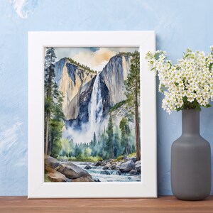 May include: A framed watercolor painting of a waterfall cascading down a cliff face in Yosemite National Park. The painting features a vibrant blue sky, lush green trees, and a rushing river in the foreground.