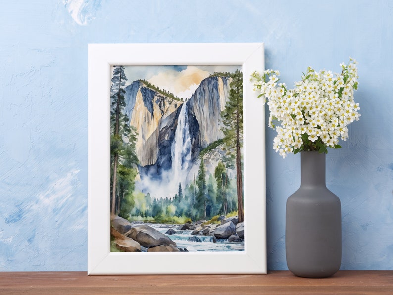 May include: A framed watercolor painting of a waterfall cascading down a cliff face in Yosemite National Park. The painting features a vibrant blue sky, lush green trees, and a rushing river in the foreground.