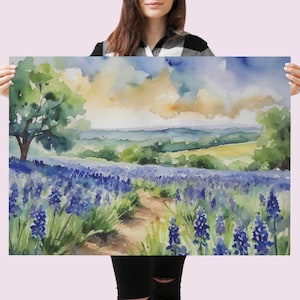 May include: Watercolour painting of a field of blue wildflowers with a dirt path leading through the centre. A green tree is in the background with a view of rolling hills and a cloudy sky.