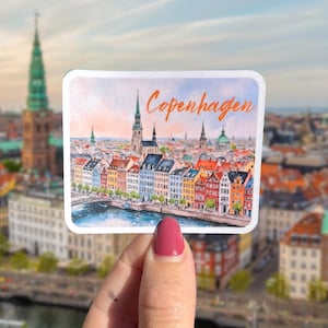 May include: A sticker featuring a watercolor illustration of the Copenhagen skyline with the word "Copenhagen" written in orange lettering.