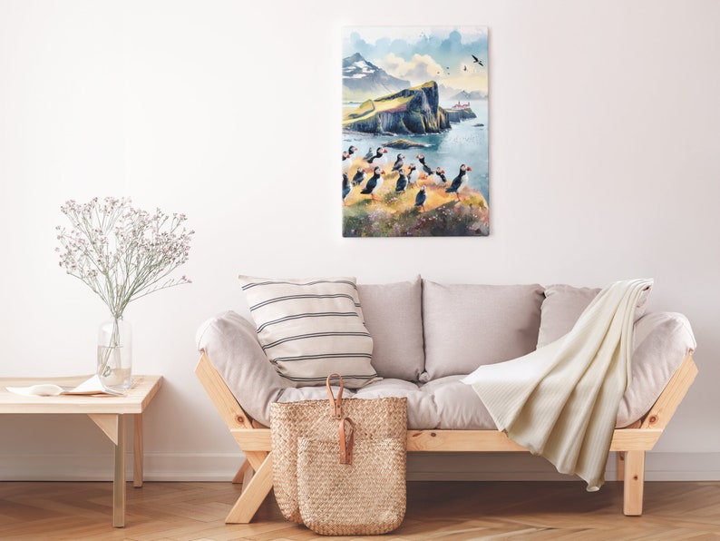 May include: A watercolor painting of a cliffside with a group of puffins standing on the edge. The painting is framed and hanging on a white wall above a light gray couch.