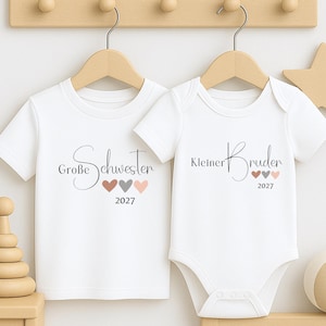 May include: A white short-sleeved t-shirt and a white short-sleeved baby bodysuit. The t-shirt features the text Große Schwester and three small hearts with the year 2027. The bodysuit features the text Kleiner Bruder and three small hearts with 2027.