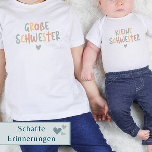 May include: A white t-shirt with the text GROBE SCHWESTER and a small heart, paired with a white baby bodysuit featuring the text KLEINE SCHWESTER and a small heart, both worn with dark blue denim pants. The text is in muted green, orange, and tan.