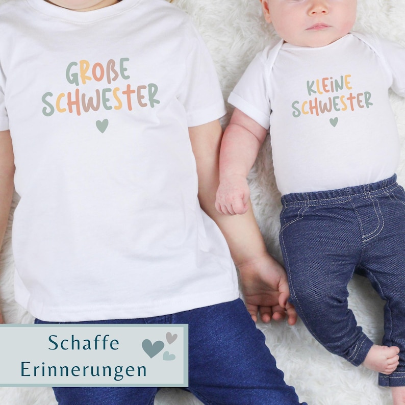 May include: A white t-shirt with the text GROBE SCHWESTER and a small heart, paired with a white baby bodysuit featuring the text KLEINE SCHWESTER and a small heart, both worn with dark blue denim pants. The text is in muted green, orange, and tan.