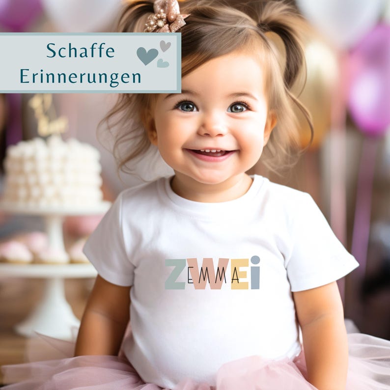May include: A white short-sleeved t-shirt featuring the text ZWEMMAI in muted pastel block letters across the chest. The shirt is worn by a toddler with hair pulled up in two pigtails, adorned with a decorative flower clip, and a pink tulle skirt.