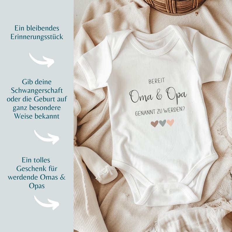 K&ouml;nnte beinhalten: Ein wei&szlig;er kurz&auml;rmeliger Babybody mit dem schwarzen Aufdruck "BEREIT Oma & Opa GENANNT ZU WERDEN?", erg&auml;nzt durch drei kleine Herzen in gedeckten Braun-, Blau- und Rosat&ouml;nen, die mittig unter dem Text platziert sind.
