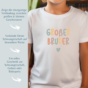 May include: A white short-sleeved t-shirt featuring the text "GROBER BRUDER" in multicolored, rounded, bubble-style letters. Below the text is a small, solid, light blue heart. The shirt is plain white with a standard crew neckline.