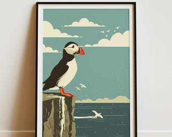 May include: A framed wall art print featuring a stylized illustration of a black and white puffin with an orange beak standing on a rocky cliff edge overlooking a dark blue sea with white clouds and several small birds flying in the sky.