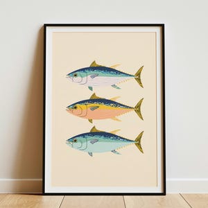 May include: A framed vertical wall art print featuring three tuna fish stacked vertically. The top fish is blue and white, the middle fish is yellow and peach, and the bottom fish is light blue and teal. All fish have yellow fins and tails.
