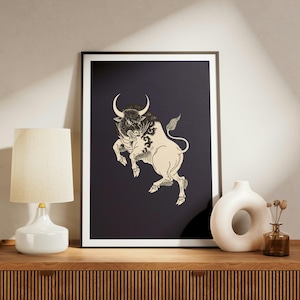 May include: A framed wall art print featuring a cream-colored illustration of a charging bull with detailed line work set against a solid dark navy blue background. The bull is depicted in a dynamic pose with curved horns and a flowing tail.