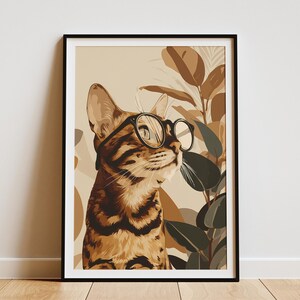 Peut inclure: Impression artistique encadrée d'un chat portant des lunettes rondes. Le chat est rayé de brun et de noir, sur un fond de feuillage brun et vert. L'œuvre est encadrée dans un cadre noir.