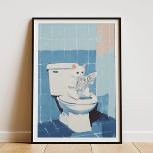 May include: A framed art print depicts a white cat sitting on a toilet, engrossed in reading a newspaper. The background features blue tiles, creating a whimsical bathroom scene. The artwork is framed in black.