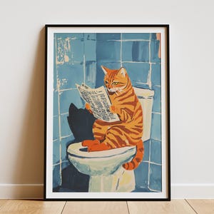 May include: Framed art print featuring an orange tabby cat reading a newspaper while seated on a toilet. The cat is in a bathroom with blue tiled walls. The artwork is framed in a black frame.