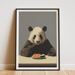 May include: A framed art print featuring a panda bear enjoying sushi with chopsticks. The panda is depicted in black, white, and brown tones, set against a gray background. A plate of sushi sits on a beige table.