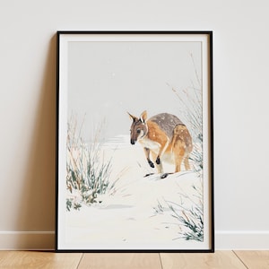 May include: Framed art print featuring a watercolor painting of a wallaby in a snowy landscape. The wallaby has brown and gray fur, and is surrounded by sparse vegetation. The artwork is displayed in a black frame.
