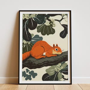 Op de afbeelding: Een ingelijste kunstdruk met een gestileerde illustratie van een eekhoorn op een tak. De eekhoorn is oranje, tegen een achtergrond van groene en crèmekleurige bladeren. Het kunstwerk is ingesloten in een zwart frame.