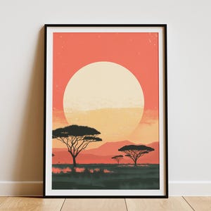 Op de afbeelding: Ingelijste kunstdruk met een zonsondergang boven een Afrikaanse savanne. Het kunstwerk toont silhouetten van bomen en bergen tegen een levendige oranje en gele lucht. De print zit in een zwart frame.