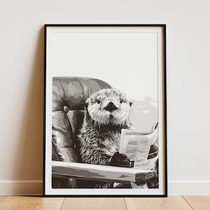 May include: Monochrome framed print featuring an otter seated in a chair, engrossed in a newspaper. The otter's fur is intricately detailed. The print is displayed on a white wall, creating a striking contrast.