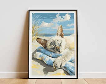 May include: Framed art print of a cat sleeping peacefully on a blue towel at the beach. The artwork features a light-colored cat with closed eyes, sandy beach, blue sky, and ocean in the background. The print is in a black frame.