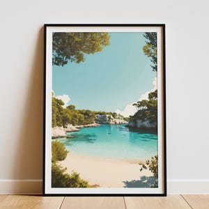 May include: A framed art print featuring a serene coastal landscape. The artwork depicts a turquoise bay with a sandy beach, surrounded by lush green trees and white cliffs under a clear blue sky. The print is encased in a black frame.