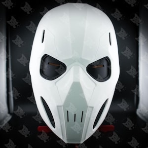 May include: A white plastic helmet with a black visor and two black eye holes. The helmet has a futuristic design with a textured surface.