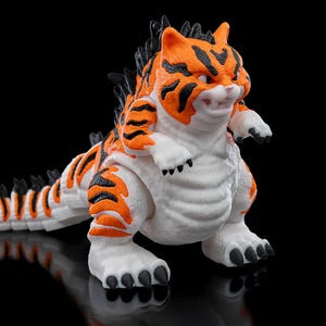 May include: A white, orange, and black tiger-like monster toy with a spiky back and sharp claws. The toy has a fierce expression and is posed in a standing position.