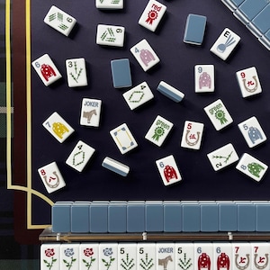 May include: A top-down view of a Mahjong set with white tiles featuring various symbols and numbers. The tiles are scattered on a dark blue surface, with a blue and green plaid pattern in the background. Some tiles have the word "JOKER" on them.