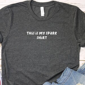 May include: A dark gray t-shirt with the text "This is my spare shirt" printed in white.