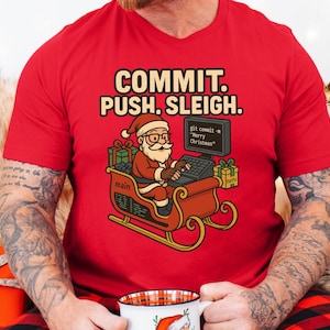 Może przedstawiać: Czerwona koszulka z napisem "COMMIT. PUSH. SLEIGH." przedstawia kreskówkowego Świętego Mikołaja kodującego na komputerze w saniach. Projekt zawiera pudełka z prezentami i wiersz poleceń z napisem "Merry Christmas."
