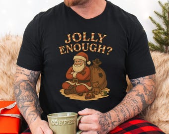 May include: Black t-shirt with a graphic of an angry Santa Claus, a sack of gifts, and the text "JOLLY ENOUGH?". Santa is wearing a red suit and hat. A teddy bear and toy blocks are also in the graphic.