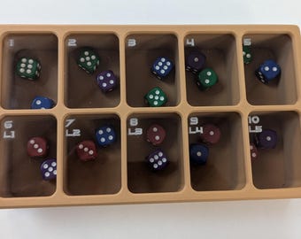 May include: A brown plastic tray with ten compartments, each labelled with a number from 1 to 10. Each compartment contains a single metal dice with different colours and numbers of dots.