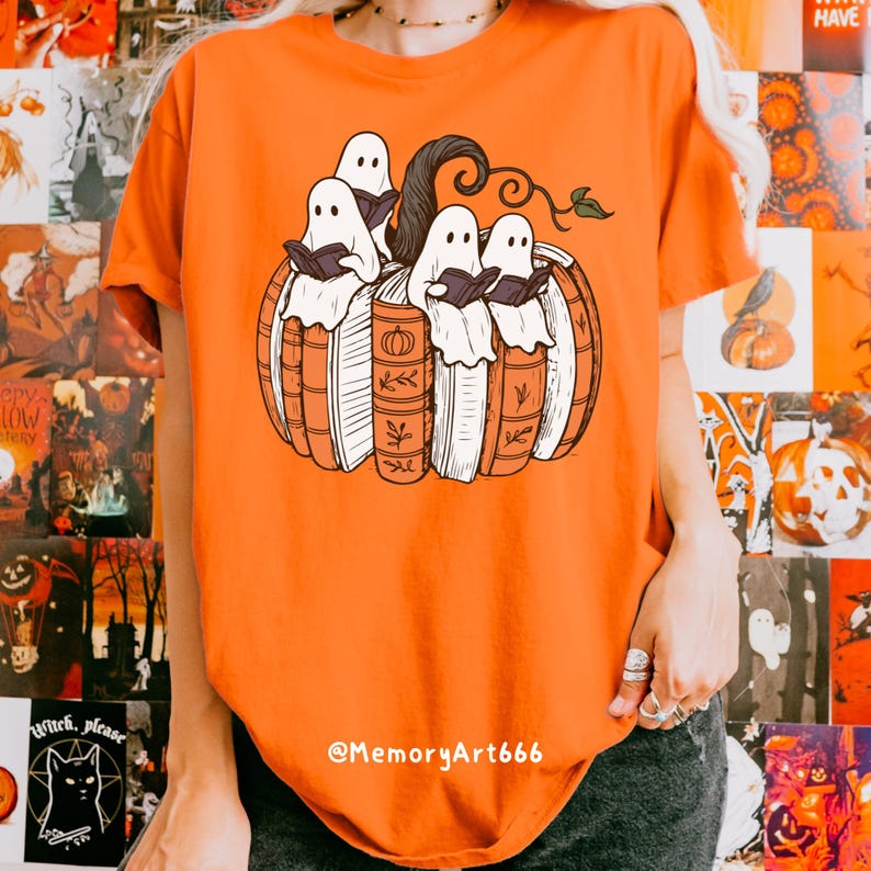 May include: Orange t-shirt featuring a pumpkin made of books with four white ghost figures reading. The pumpkin has a dark brown stem and green leaves. The text "@MemoryArt666" is at the bottom.