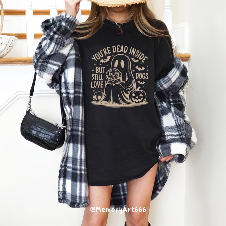 May include: Black t-shirt with a graphic of a ghost holding a dog. The text on the shirt reads "You're Dead Inside But Still Love Dogs".