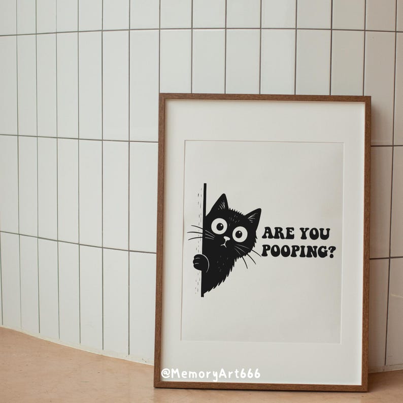 May include: A framed art print featuring a black cat peeking from behind a wall. The cat has large, expressive eyes and whiskers. The text "ARE YOU POOPING?" is printed in bold, black letters. The frame is brown.