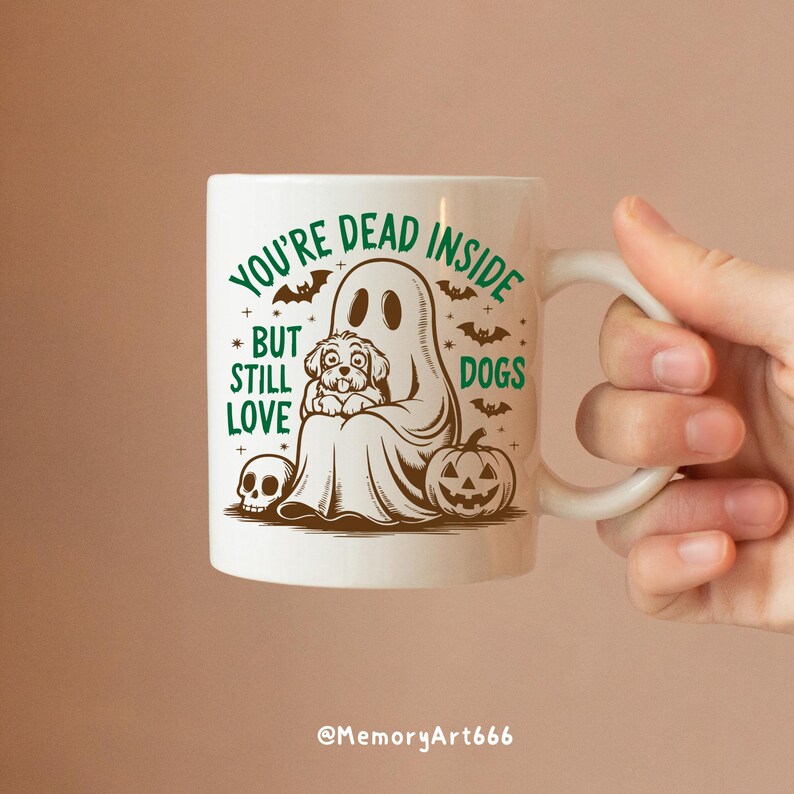 May include: White ceramic coffee mug with a green and brown illustration of a ghost holding a dog. The text on the mug reads "You're Dead Inside But Still Love Dogs".