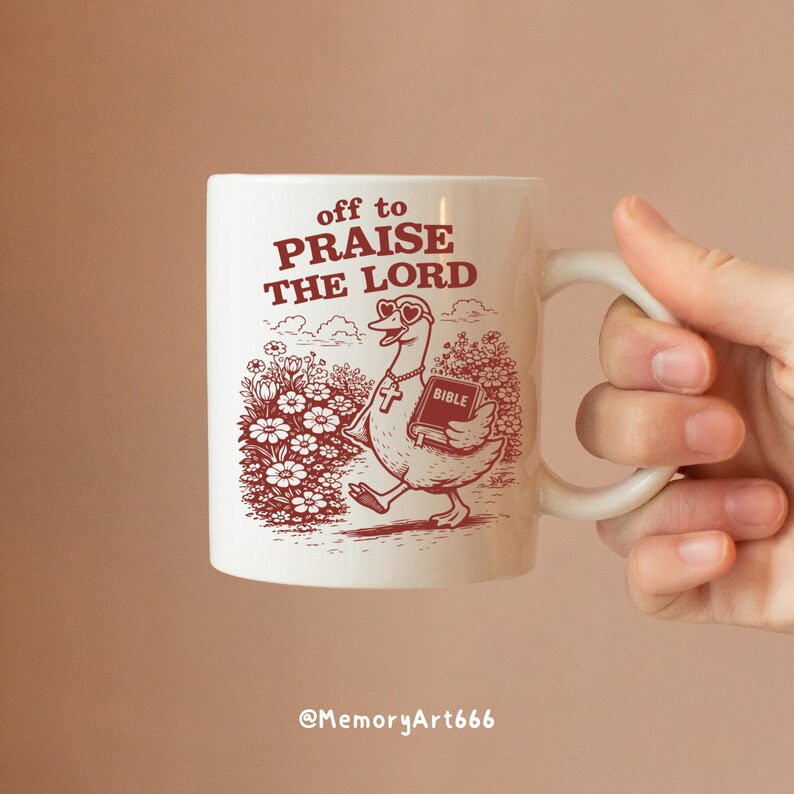Op de afbeelding: Witte keramische mok met een illustratie van een gans met een hartvormige zonnebril en een kruis, die een bijbel draagt. De mok heeft de tekst "off to PRAISE THE LORD" in het rood.