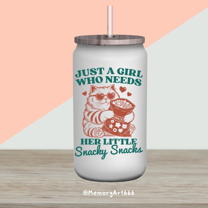 May include: White stainless steel tumbler with a green and white design. The tumbler features a cartoon cat wearing sunglasses and holding a bag of snacks. The text on the tumbler reads "Just a girl who needs her little snacky snacks".